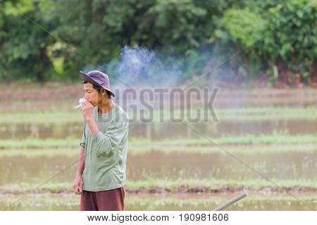 CHIANG RAI THAILAND - JUNE 16 : Unidentified asian male farmer smoking during working in the field on June 16 2017 in Chiang rai Thailand. Horizontal photo with copyspace