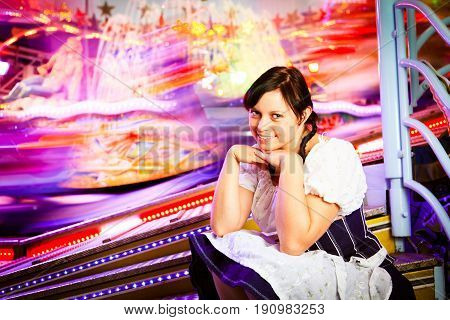 young woman sitting next to brightly colored carousel
