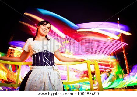 young woman standing next to brightly colored carousel