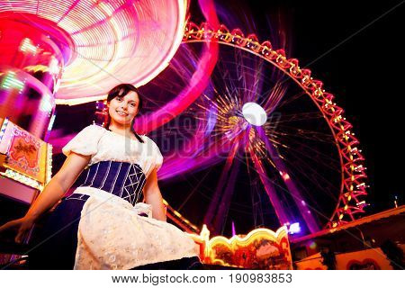 young woman standing next to brightly colored carousel