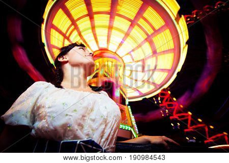 young woman standing next to brightly colored carousel