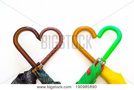 Creative image umbrellas of different colors with handles close-up heart symbol on white background holiday love