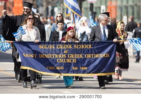 Chicago, Illinois, USA - April 29, 2018 Members of the Solon Greek School of Saint Demetrios Greek Orthodox Church wearing traditional clothing and waving greek flags at the Greek Independence  Day Parade