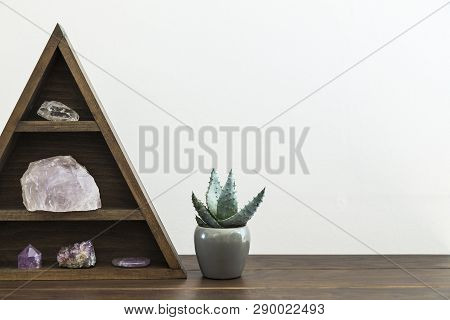 Triangular Wooden Crystal Shelf On A Wooden Surface With Potted Succulent Plant