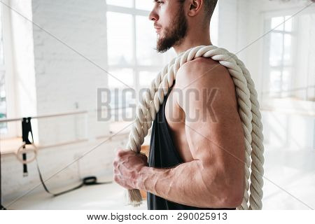 Strong Male Athlete Holding On Shoulder Rope After Intense Workout. Portrait Of Fitness Man With Bat