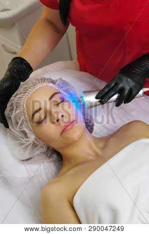 Hardware Cosmetology. Ultrasound Chromotherapy. Beautician Carries Out Procedure For Tightening Skin