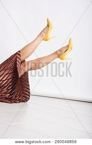 Woman's legs up in the air with yellow high heeled shoes. Beauty and fashion abstract conception.