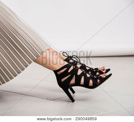 Young and trendy female legs with black high heeled shoes with heels on the ground. Studio abstract shot, body parts.