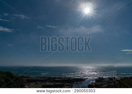 Back-lit Ocean Scene Darkened By Lens Flare From Sun Over Horizon.