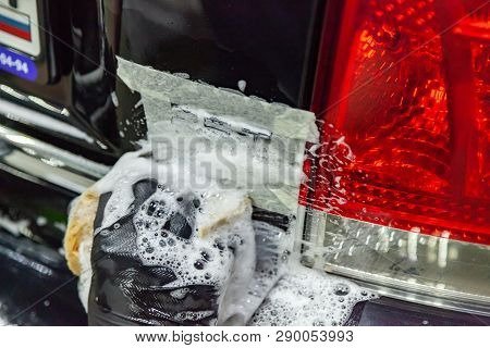 Thorough And Painstaking Washing Of Car Parts In The Form Of Emblems In A Black Glove With A Sponge 