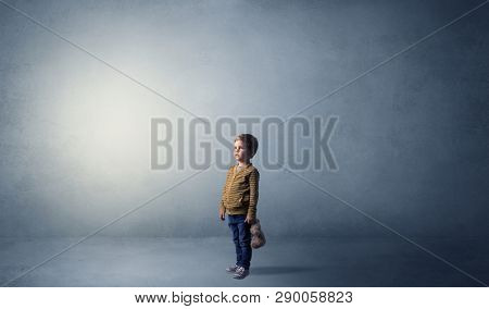 Little waggish kid staying alone in a big empty room with his plush