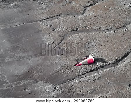 Traffic Cone Left And Partially Buried In Sand Shore Of Brisbane River, Australia.