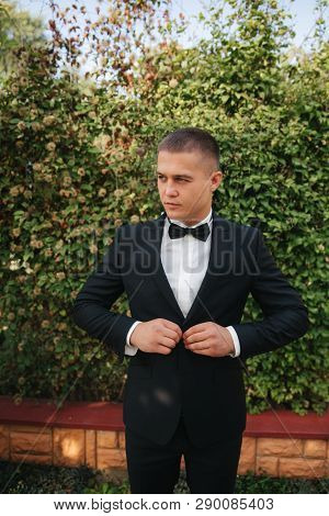 Young Man Walking In The Park. Handsome Groom In Black Suit