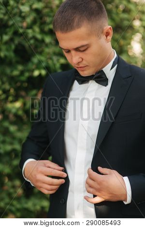 Young Man Walking In The Park. Handsome Groom In Black Suit