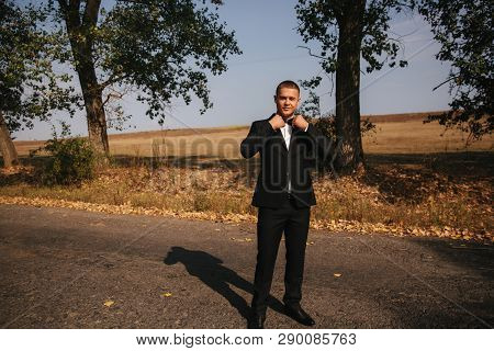 Young Man Walking In The Park. Handsome Groom In Black Suit