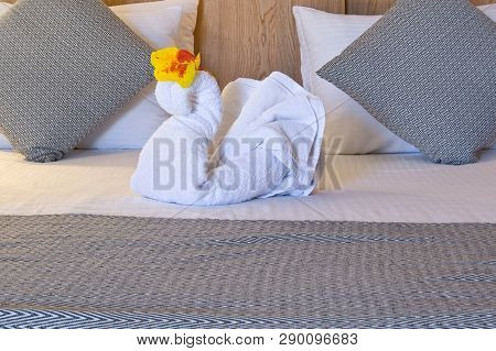 White Towel Swan With Frower On Double Bed In Hotel Room