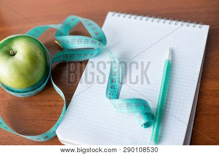 Planning Of A Diet. A Notebook C An Inscription - The Diet, A Measuring Tape, An Apple And Pen, Clos