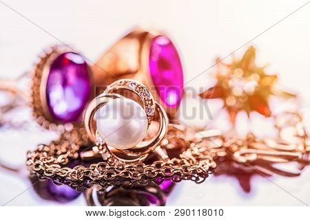 Elegant Luxury Composition Of Gold Jewelry With Pearl Ring, Amethysts And Rubys Gemstones On Light B