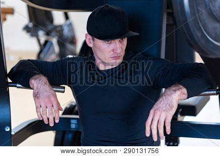 Portrait Of Male Athlete Wearing Cap Sitting At Gym