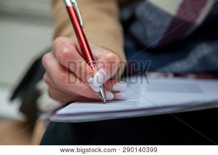 Woman Hand With Red Pen Completing A Form.