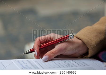Woman Hand With Red Pen Completing A Form.