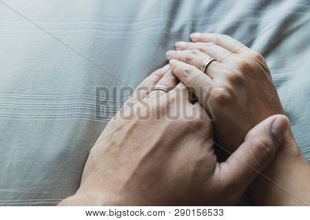 Close Up Husband And Wife Hands Together On Gray Beds And Beautiful Wedding Rings