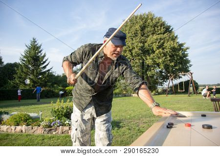 Man Playing Novuss In Outdoors. Novuss Is A National Sport In Latvia Similar To Pocket Billiards Or 