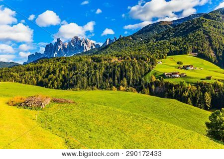 Picturesque farms with red roofs are built on the mountains. Delightful mountain valley in the Dolomites. Wonderful day in South Tyrol. The concept of ecological and photo tourism