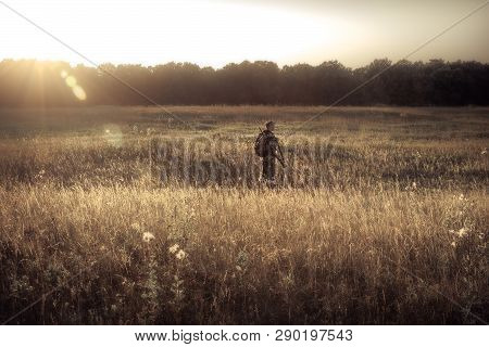 Hunter Men Hunting In Rural Field Nearby Forest At Sunset During Hunting Season