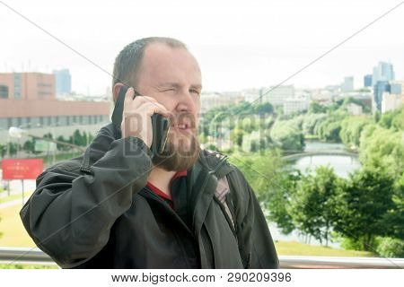 Business Mature Male Tourist With A Beard Talking On The Phone And Make An Appointment On The Backgr