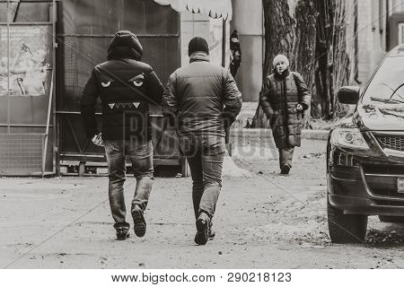 Dnipro, Ukraine - March 2, 2019: Two Men Walking Down The Street. Bulldog Face Design On Coat Back. 