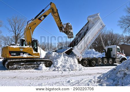 Sabin, Minnesota, March 11, 2019: The Cat 319d, An Excavating Machine Removing Snow From A Truck Box