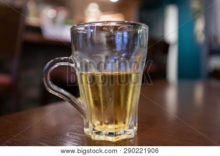Glass Half Empty Or Half Full Sits On Wooden Table With Blurred Background