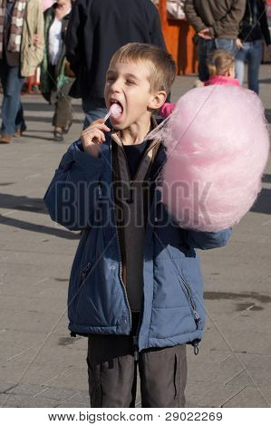 Boy eating cotton candy in the street