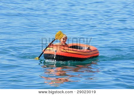Muchacho en el barco de remo por el lago (mar)