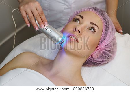 Hardware Cosmetology. Ultrasound Chromotherapy. Beautician Carries Out Procedure For Tightening Skin