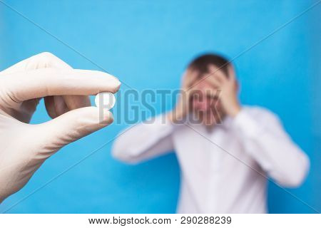 Doctor Holding A Pill For Headache Against The Background Of A Man Who Has A Headache, Concept Pills