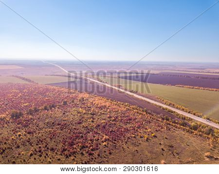 Beautiful countryscape with agricultural fields, meadows and forests on a background of a blue clear sky in the autumn. Bird's eye aerial view from drone.