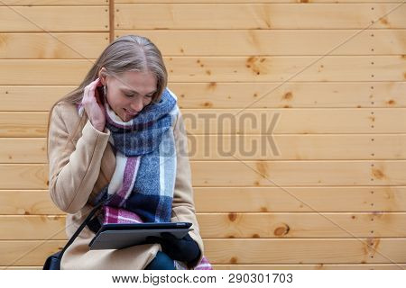 Blonde Beautiful Woman Holding Tablet Outdoor. Portrait Of Young Woman Wearing Tartan Scarf In Front