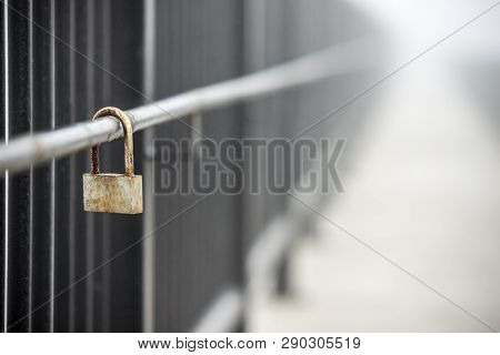 Lone Rusty Lock On The Railing With A Blurred Background. Loneliness, Old Age.