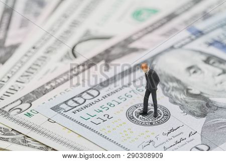 Miniature Businessman Leader Standing And Thinking On Us Federal Reserve Emblem On Five Dollars Bank