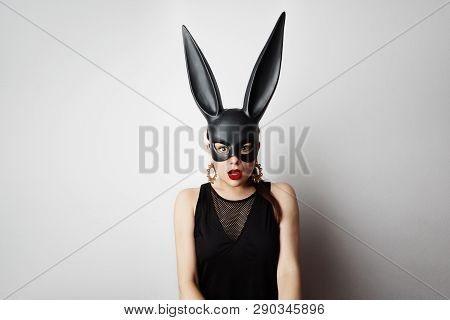 Sexy Young Woman With Red Lipstick And Large Breasts Wearing A Black Mask. Easter Bunny Standing On 
