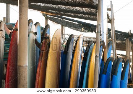 Set Of Different Color Surf Boards In A Stack By Ocean.bali.indonesia. Surf Boards On Sandy Beach Fo