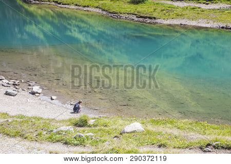 A Boy Watching The Lake Called Nassfeld Speicher In Hohe Tauern National Park In Austria