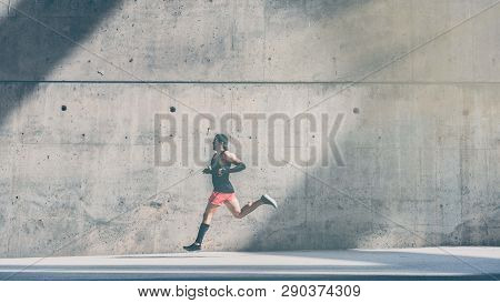 Muscular Male Sprinter Athlete Running Fast, Exercising Outdoors, Jogging Outside Against Gray Concr