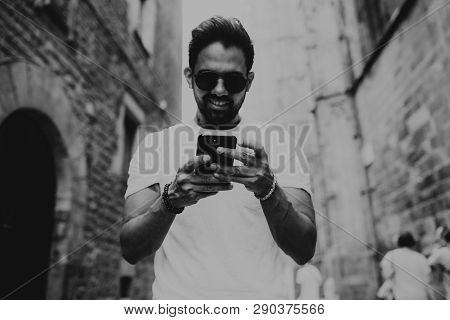 Handsome Bearded Hispanic Man Using Mobile Smartphone For Surfing Web Internet, Making Call And Look