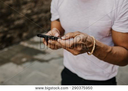 Handsome Bearded Hispanic Man Using Mobile Smartphone For Surfing Web Internet, Making Call And Look