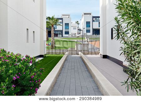 Narrow Footpath Along Between Two White Residential Houses Path Leading To Green Lawn Inside Of Resi