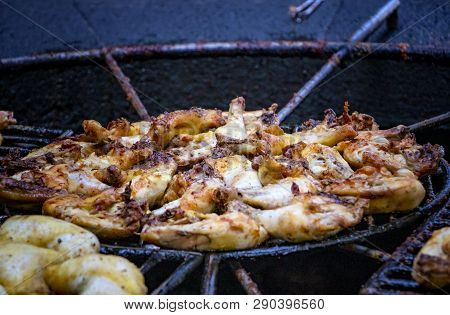 Chicken Pieces Are Baked And Roust On A Grill Above The Volcanic Stone.