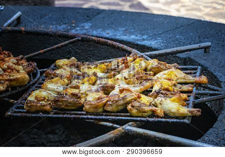 Chicken Pieces Are Baked And Roust On A Grill Above The Volcanic Stone.